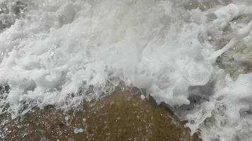 lento movimento do ampla onda quebra em a de praia com espuma e surfar video