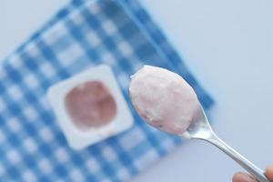 fresh yogurt in a plastic container and spoon on table photo