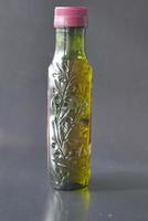 bottle of olive oil and olive leaves on yellow photo