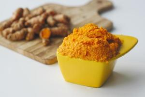 turmeric root and paste in a bowl on white background photo