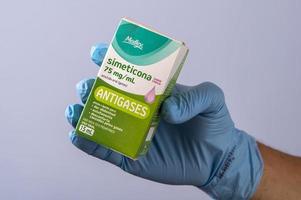 Rio, Brazil - January 27, 2023, hand with protective rubber glove holding medicine box, simethicone photo