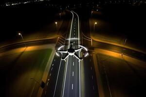 The drone flies at night on the road, illuminating with spotlights. . photo