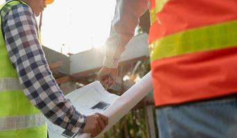 inspector or engineer is inspecting construction and quality assurance new house using a blue print. Engineer or architects or contactor work to build the house before handing it over to the homeowner photo