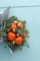 Christmas bouquet of fir branches, mandarins and little gift boxes on blue background. New Year. selective focus. photo