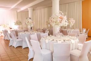 decoración festiva de la boda. hermosas flores blancas y rosas frescas en un jarrón de vidrio en la mesa del comedor el día de la boda. foto de alta calidad