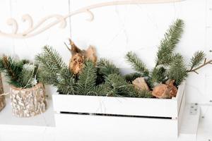 Christmas composition. Wooden box with Christmas fir branches and lighting garlands, on wooden white background. Merry Christmas, New Year, Happy Holidays, Template. Greeting card. 2023 photo