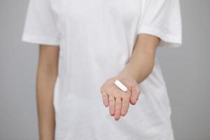 woman dressed in white t shirt, holding a clean tampon in her hands, close-up. female hygiene products, menstruation photo