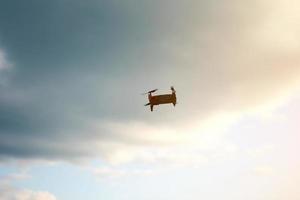 Hovering drone flying upward on a cloudy sky backdrop. copter flying . photo