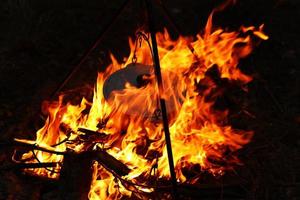 Cooking outdoors in field conditions. Cauldron on a fire in the forest. Cooking at the stake while traveling. Tripod with a bowler hat on a fire on picnic. Conceptual travel, trekking and adventure photo