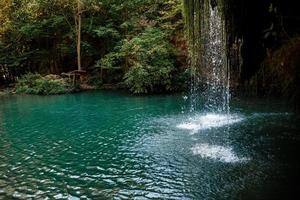 Long exposure waterfall during the day. green forest and rocky mountain. summer time. crystal clear blue water. beautiful waterfall with blue lake in the forest. photo