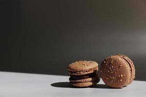 Sweet brown chocolate french macaroons or macarons dessert isolated on white background with light rays from window. copy space. photo