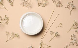 Open empty noodle bowl with and pair of wooden sticks on beige background, top view photo