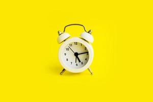 White alarm clock on a yellow background. Empty space for text. photo