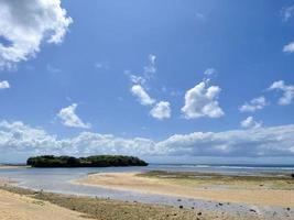 hermosa playa con un ver de el línea costera azul cielo y blanco nubes foto