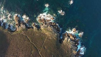 Haut vue de océan vagues éclabousser sur sisarga îles côte par le rivage dans galice, Espagne. aérien video