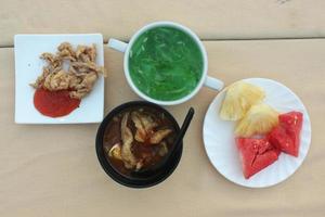 fasting appetizer with sliced fruit, soup, cucumber juice and fried chicken skin photo