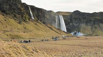 Gruppen von Tourist Besuch gehen auf Wege durch schön Wasserfall von seljalandsfoss im Frühling video