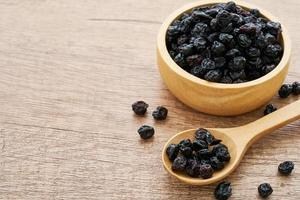 dry blueberry or blackberry in wood plate and spoon on wooden table background. pile of dry blueberry or blackberry. dry blueberry or blackberry photo