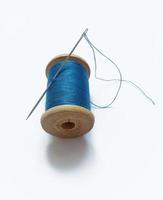 A spool of blue thread with a needle on it photo