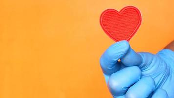 läkare hand i latex handskar innehav röd hjärta stänga upp video