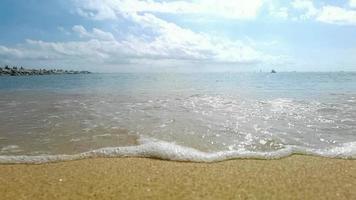 lento movimento do ampla onda quebra em a de praia com espuma e surfar video