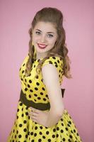 Portrait of a retro girl. Woman in a yellow dress on a pink background. photo