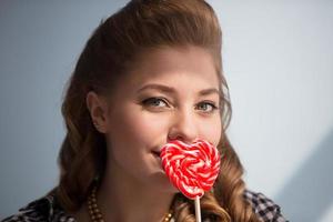 hermosa niña con un rojo caramelo en el formar de un corazón foto