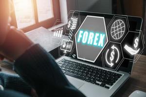 forex comercio, joven hombre utilizando teléfono inteligente y ordenador portátil computadora con forex icono en vr pantalla en escritorio, en línea inversión. negocio, Internet y tecnología concepto. foto