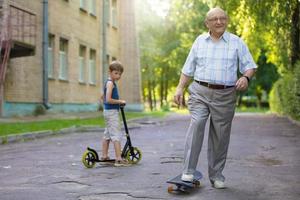 Grandfather and grandson on a walk. A child is watching his grandfather ride on a skateboard. photo