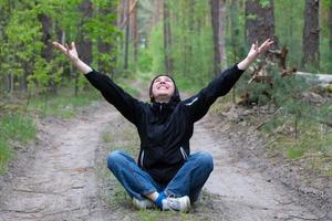 Man in the forest. A middle-aged woman sits on a forest road. photo