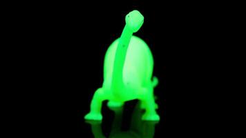 A glowing green dinosaur spinning around against a black background video
