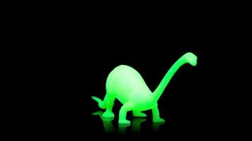 un brillante verde dinosaurio hilado alrededor en contra un negro antecedentes video