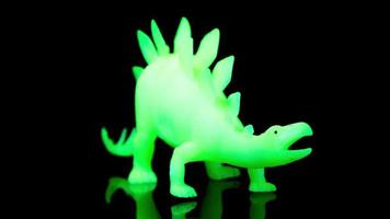 un brillante verde dinosaurio hilado alrededor en contra un negro antecedentes video