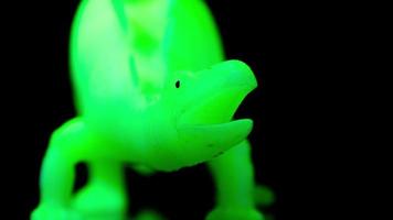 een gloeiend groen dinosaurus spinnen in de omgeving van tegen een zwart achtergrond video