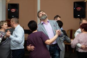 Middle-aged people dance in a restaurant. photo