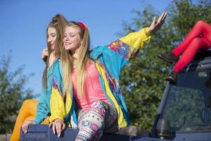 Beautiful country girls dressed in the style of the nineties sit on a tractor. photo