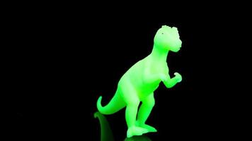 un brillante verde tirano saurio Rex dinosaurio hilado alrededor en contra un negro antecedentes video