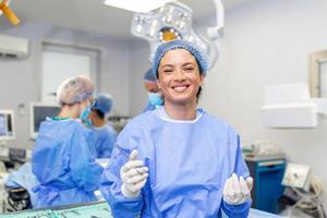 Portrait of happy woman surgeon standing in operating room, ready to work on a patient. Female medical worker in surgical uniform in operation theater. photo