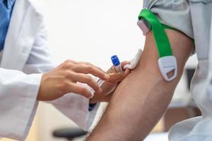 Preparation for blood test by female doctor medical uniform on the table in white bright room. Nurse pierces the patient's arm vein with needle blank tube. photo