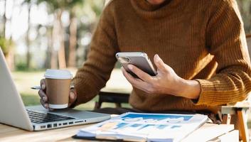 mujer de negocios utilizando móvil teléfono, tableta.de cerca en borroso verde antecedentes foto