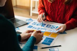UX developer and ui designer brainstorming about mobile app interface wireframe design with customer breif and color code at office. photo