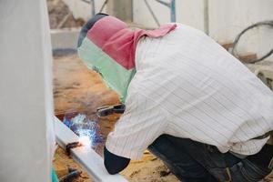 construction man is welding steel roof structure, people working in construction site concept photo