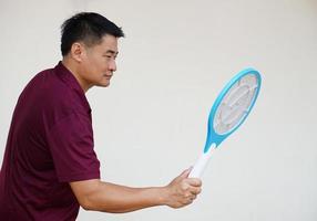 Asian man holds  mosquito electric swatter racket. Concept, Technology electric device to kill mosquitoes, insects, bugs by swatting to flying insects that can cause disease or annoyed feeling. photo