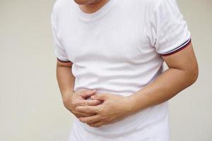 hombre tiene un Dolor de estómago, usos su manos a toque abdomen. concepto, salud problemas. intestino o estómago enfermedades. sensación herir y sufrir desde físico enfermedad en diario vida. foto