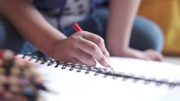 dichtbij omhoog van een kind hand- tekening met gekleurde potlood Aan een bladzijde video