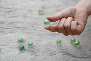 Closeup hand holds round small mable balls to play games. Concept, traditional childen play toy. Recreation activity to make concentrate for kids, fun and competition games photo
