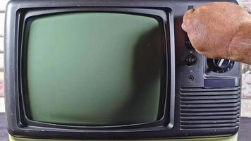 Mens hand- afstemmen oud televisie met grijs interferentie scherm kanaal video