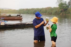 asiático hombre profesor es enseñando su estudiante exterior, estudiar ecología sujeto, explorar agua desde naturaleza fuente. concepto, educación. aprendizaje por haciendo. vida experiencia foto