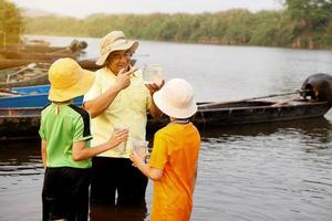 asiático hombre profesor es enseñando su estudiantes exterior, estudiar ecología sujeto, explorar agua desde naturaleza fuente. concepto, educación. aprendizaje por haciendo. vida experiencia. foto