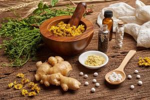 concepto de homeopático pastillas en un de madera cuchara y botellas con el hierba en un mortero con un mano de mortero en de madera mesa antecedentes foto